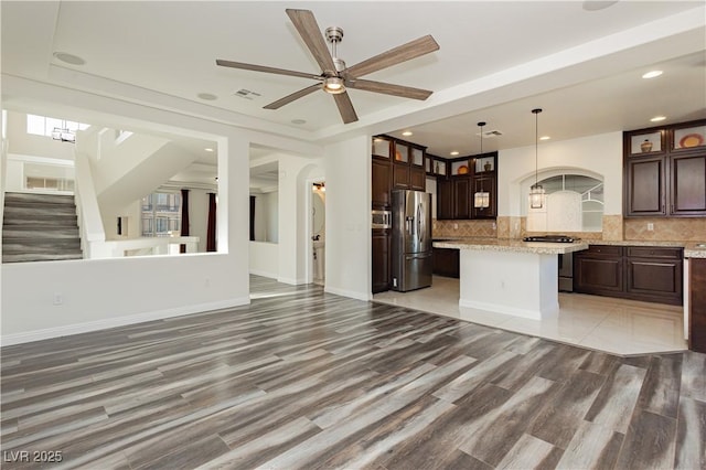 kitchen featuring a kitchen island, stainless steel appliances, decorative light fixtures, and dark brown cabinets