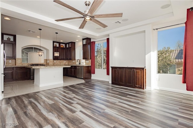 kitchen featuring pendant lighting, sink, backsplash, stainless steel range with gas stovetop, and a center island