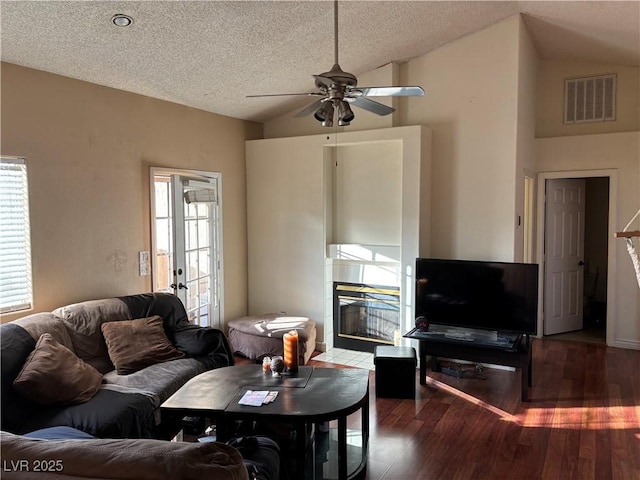 living room with dark hardwood / wood-style flooring, a fireplace, a wealth of natural light, and vaulted ceiling