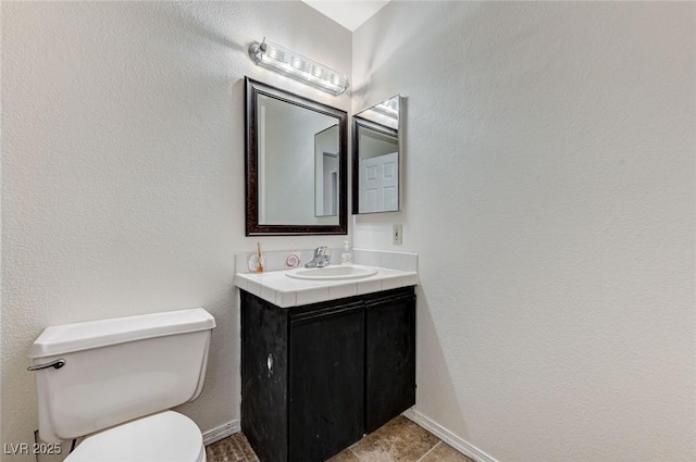 bathroom featuring vanity, toilet, and baseboards