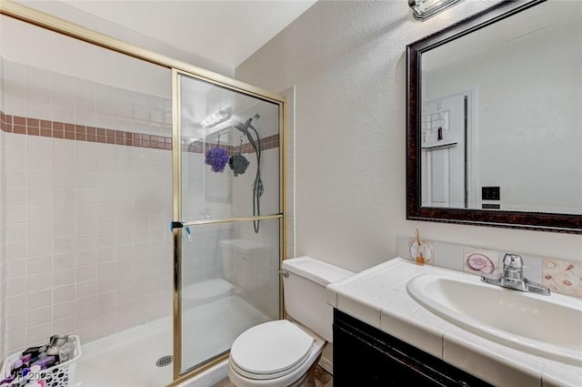 full bathroom with a textured wall, a stall shower, vanity, and toilet