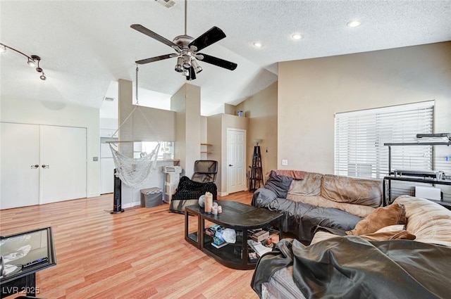 living room featuring light wood-style floors, vaulted ceiling, a textured ceiling, and a ceiling fan