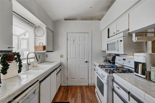 kitchen with tile countertops, white appliances, dark wood-type flooring, a sink, and white cabinets