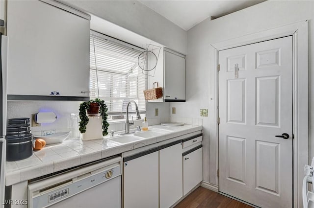 kitchen with tile countertops, dark wood-type flooring, white cabinetry, a sink, and dishwasher