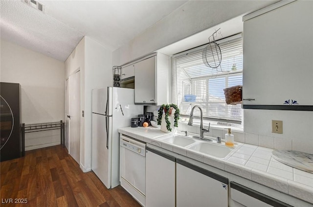 kitchen with white appliances, dark wood-style flooring, a sink, white cabinetry, and tile counters