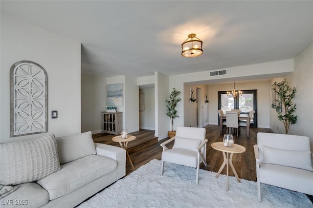 living room featuring dark wood-type flooring and an inviting chandelier