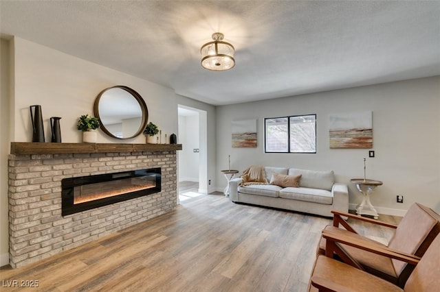 living room with a brick fireplace, light hardwood / wood-style floors, and a textured ceiling