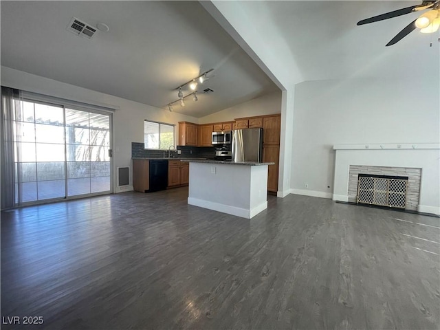 kitchen with lofted ceiling, sink, dark hardwood / wood-style floors, a tile fireplace, and stainless steel appliances