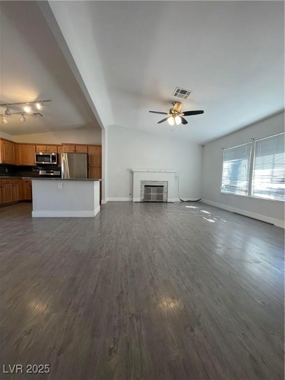 unfurnished living room featuring vaulted ceiling, dark hardwood / wood-style floors, and ceiling fan