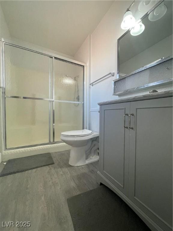 bathroom with walk in shower, vanity, toilet, and hardwood / wood-style floors