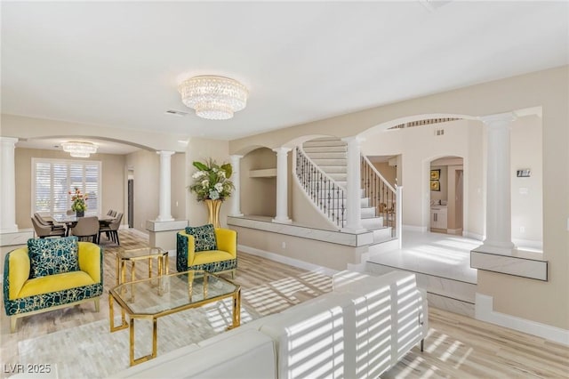 living room featuring decorative columns, a chandelier, and light hardwood / wood-style floors