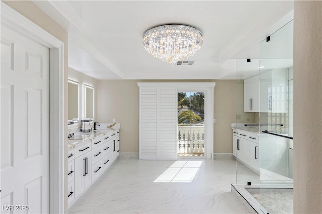 kitchen with white cabinetry, sink, a chandelier, hanging light fixtures, and light stone countertops