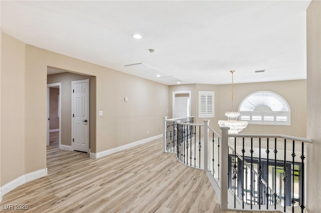 corridor with an inviting chandelier and light hardwood / wood-style flooring