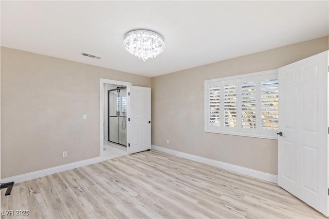 spare room with a notable chandelier and light hardwood / wood-style floors