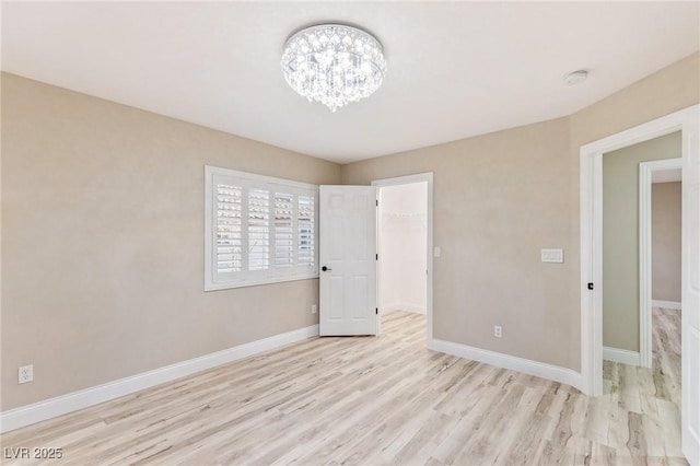 unfurnished bedroom with a walk in closet, a chandelier, light hardwood / wood-style floors, and a closet