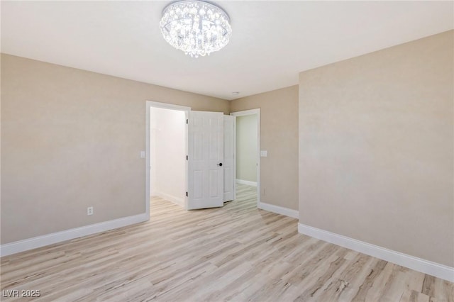 unfurnished room with an inviting chandelier and light hardwood / wood-style flooring