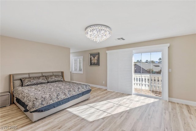 bedroom featuring an inviting chandelier, access to outside, and light hardwood / wood-style floors