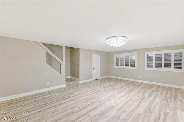 spare room featuring an inviting chandelier and light hardwood / wood-style floors