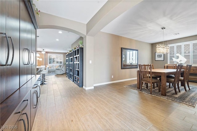 dining area with ceiling fan with notable chandelier and light hardwood / wood-style floors