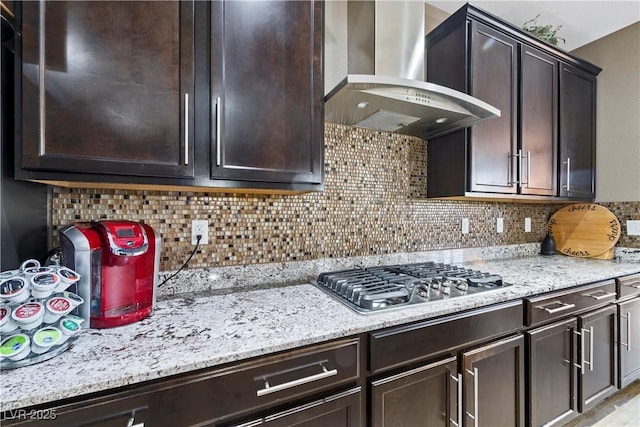 kitchen with stainless steel gas stovetop, tasteful backsplash, dark brown cabinets, and wall chimney range hood