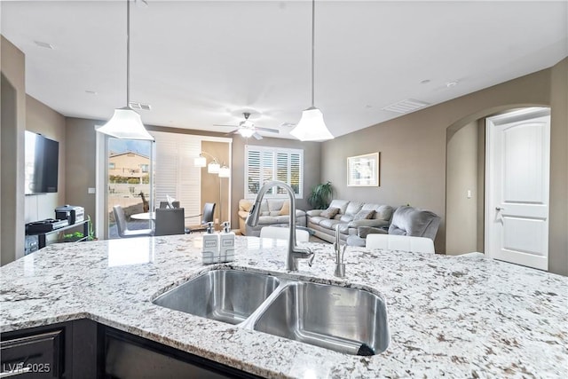 kitchen featuring sink, light stone counters, and decorative light fixtures