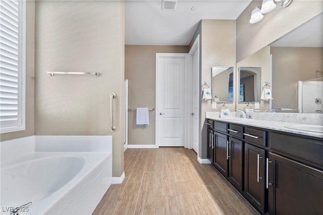 bathroom featuring vanity, wood-type flooring, and plus walk in shower