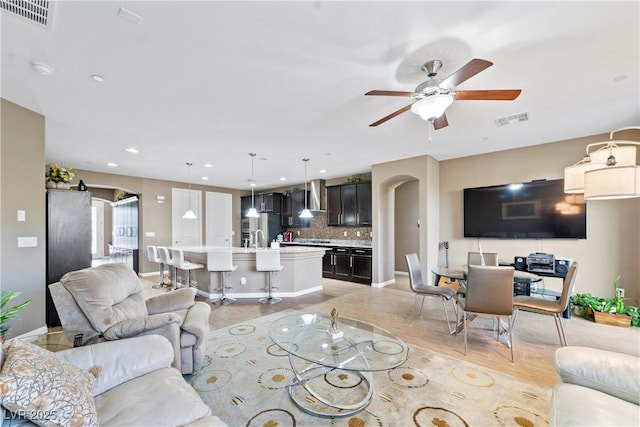 living room with sink, light hardwood / wood-style flooring, a barn door, and ceiling fan