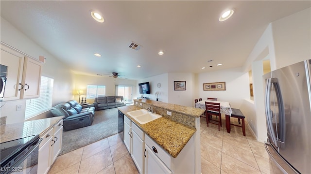 kitchen featuring stainless steel refrigerator, white cabinetry, sink, electric range, and light stone counters