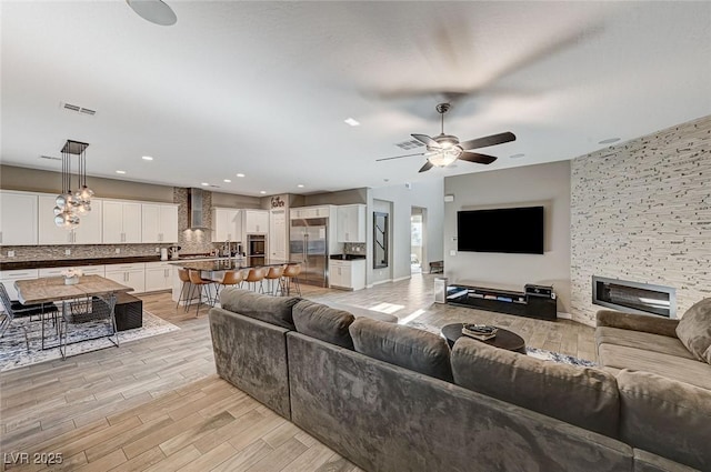 living room featuring ceiling fan and a fireplace