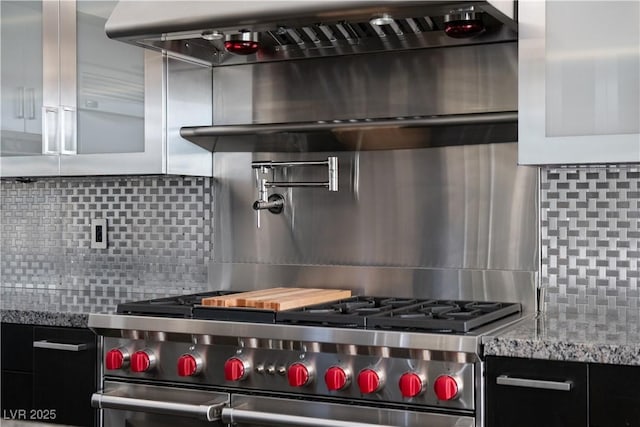 kitchen featuring light stone counters, high end stove, extractor fan, and decorative backsplash