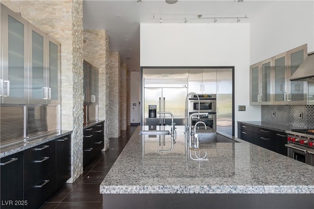 kitchen featuring track lighting, high quality appliances, sink, and a kitchen island with sink