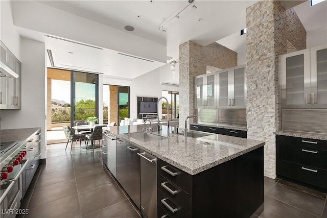 kitchen featuring rail lighting, sink, a center island with sink, and white cabinets