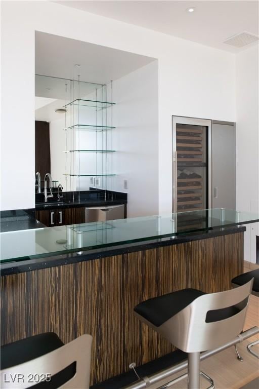 bar with dark brown cabinetry, sink, and stainless steel dishwasher