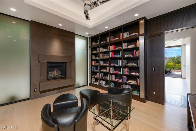 living area with built in shelves, a large fireplace, and light wood-type flooring