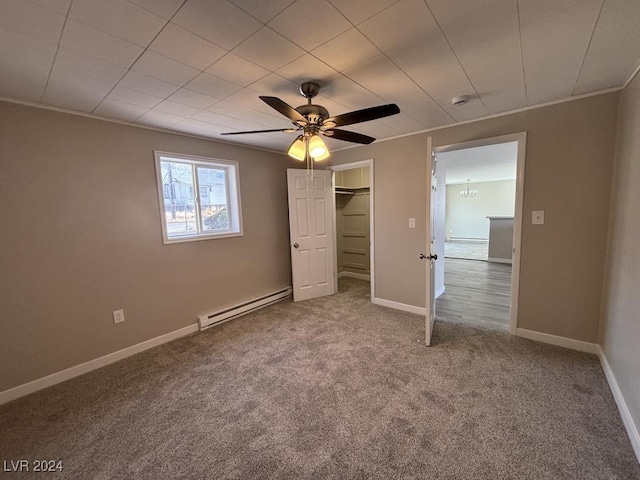 unfurnished bedroom with a baseboard radiator, carpet floors, ornamental molding, a spacious closet, and ceiling fan