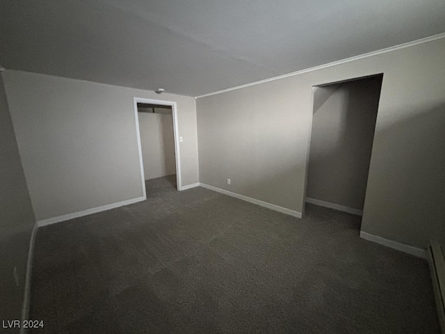 unfurnished bedroom with a baseboard heating unit and dark colored carpet