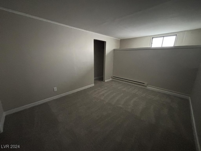 unfurnished room featuring a baseboard heating unit and dark colored carpet