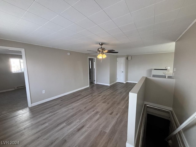 unfurnished living room featuring a baseboard heating unit, hardwood / wood-style floors, and ceiling fan