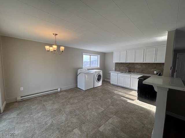 washroom featuring a baseboard heating unit, sink, washing machine and clothes dryer, and an inviting chandelier