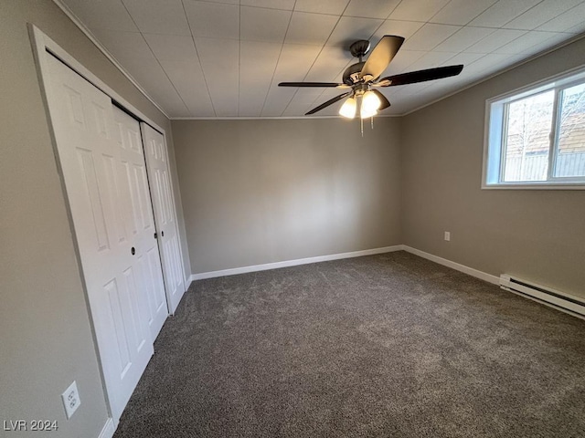 unfurnished bedroom featuring ceiling fan, dark carpet, a closet, and a baseboard heating unit