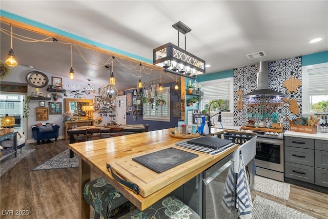 kitchen featuring wall chimney exhaust hood, wood-type flooring, decorative light fixtures, gray cabinets, and stainless steel electric stove