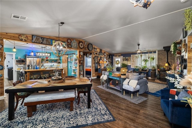 dining room with vaulted ceiling, a wood stove, ceiling fan, and dark hardwood / wood-style flooring