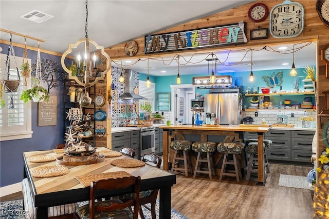 dining room featuring hardwood / wood-style flooring, lofted ceiling, and an inviting chandelier