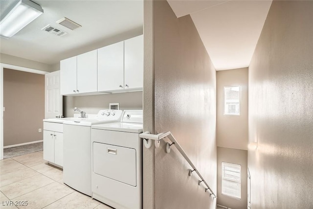 clothes washing area with light tile patterned flooring, cabinets, washer and clothes dryer, and sink