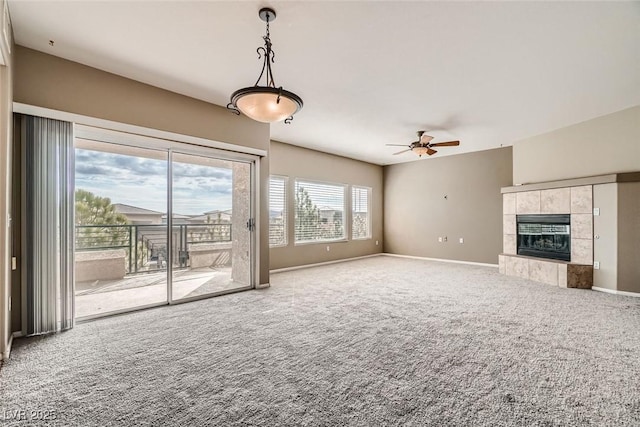 unfurnished living room featuring a tiled fireplace, ceiling fan, and carpet