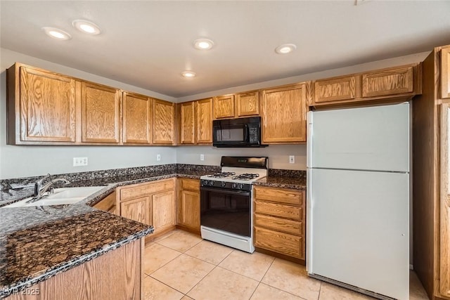 kitchen with sink, light tile patterned floors, white refrigerator, range with gas stovetop, and dark stone counters