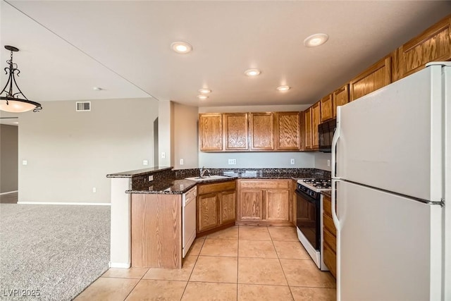 kitchen featuring sink, white appliances, hanging light fixtures, light colored carpet, and kitchen peninsula