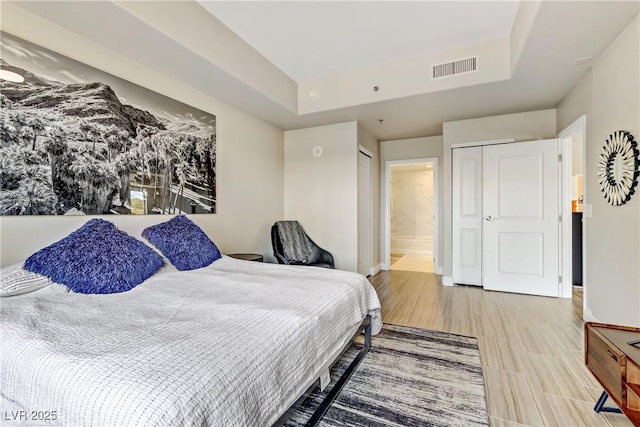 bedroom with connected bathroom and a raised ceiling