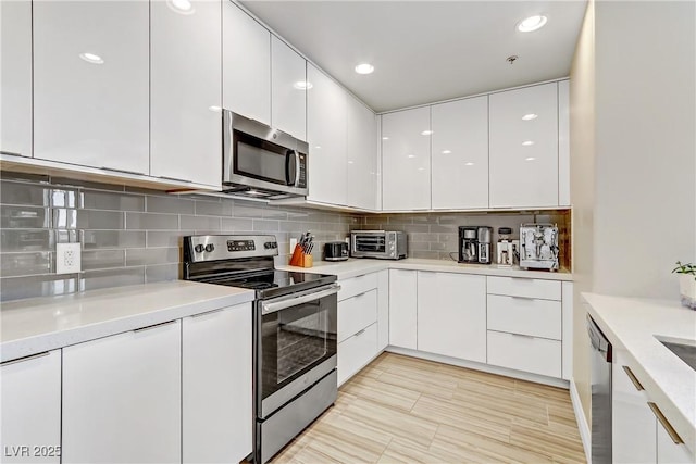 kitchen featuring decorative backsplash, white cabinets, and appliances with stainless steel finishes