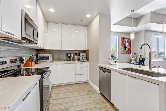 kitchen featuring white cabinetry, stainless steel appliances, sink, and pendant lighting